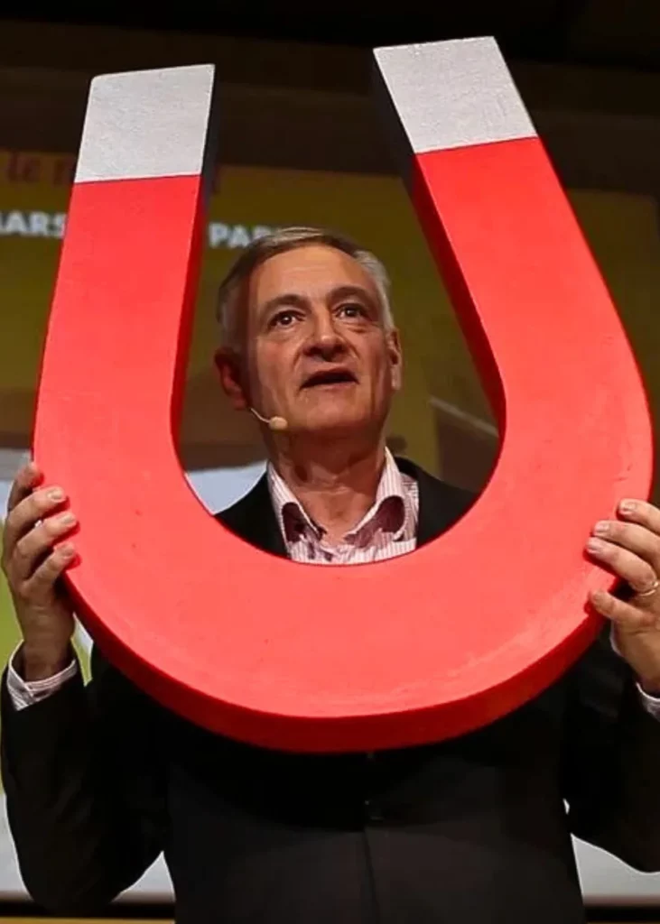 Jean-Luc Hudry en conférence avec un aimant géant pour illustrer l’Optimisme Opérationnel, le changement et l’art de penser autrement en entreprise.
